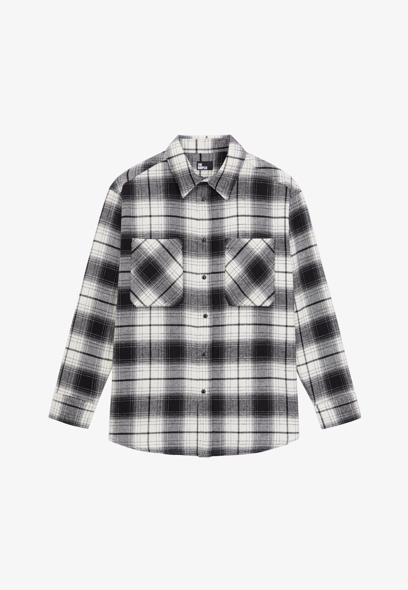 Chemise en flanelle à carreaux noirs et blancs, manches longues, fermeture boutonnée sur le devant et deux poches poitrine.