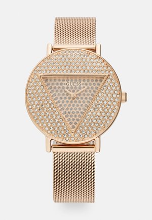 Okretni sat s mrežastom trakom u ružičastom zlatom i sjajnim licem prekrivenim kristalima, koje sadrži trokutasti dizajn i minimalističke kazaljke.