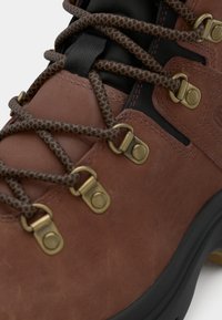 Pruun nahast matkajalats, millel on metallist silmad ja tekstureeritud nöörid. Kummist tallad ja tugevdused tagavad vastupidavuse ja toe.