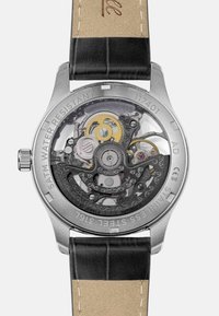 Automatisch horloge met een roestvrijstalen achterkant, zwart leren band en zichtbare tandwielen. Waterdicht tot 5 ATM, heeft 22 edelstenen.