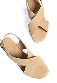 Beige suède slingback sandlid, mille lõikega ülemine osa, avatud varvas ja minimalistlik rihm metallist pandlaga aktsendiga.