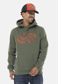 Un hoodie vert avec une poche avant, arborant un logo imprimé orange et noir. Assorti à une casquette bleue et orange. Tissu et design décontractés.