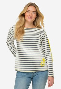 Maglietta a maniche lunghe a righe in crema e blu navy, con accenti gialli a forma di stella a sinistra e motivo a righe su tutto il capo. Vestibilità casual e texture morbida.