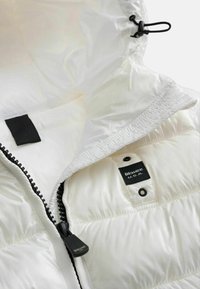 Gilet imbottito bianco con chiusura a zip, tirazip nero e etichetta con la scritta "Blauer U.S.A.". Presenta un cappuccio strutturato e una consistenza liscia.