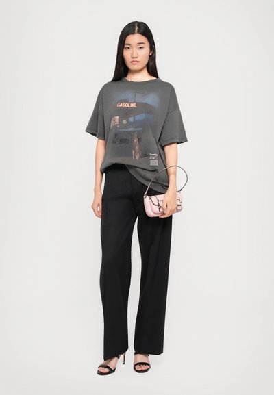Gray oversized t-shirt with a "GASOLINE" graphic and text, paired with black wide-leg trousers. Accessorized with a small pink handbag.