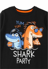 Sort t-shirt med tegneserie-hajer, der holder madvarer. Hajen til venstre er blå og bærer en hamburger; den til højre er orange og holder pizza.