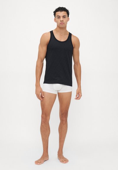 Schwarzes Tanktop mit dezentem Streifenmuster, kombiniert mit weißen Unterhosen. Das Tanktop hat einen Rundhalsausschnitt und eine lässige Passform.