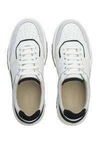 Witte sneakers met zwarte accenten, gemaakt van leer en suede, geperforeerde neus, dikke zool en platte veters. Merk zichtbaar aan de binnenkant.