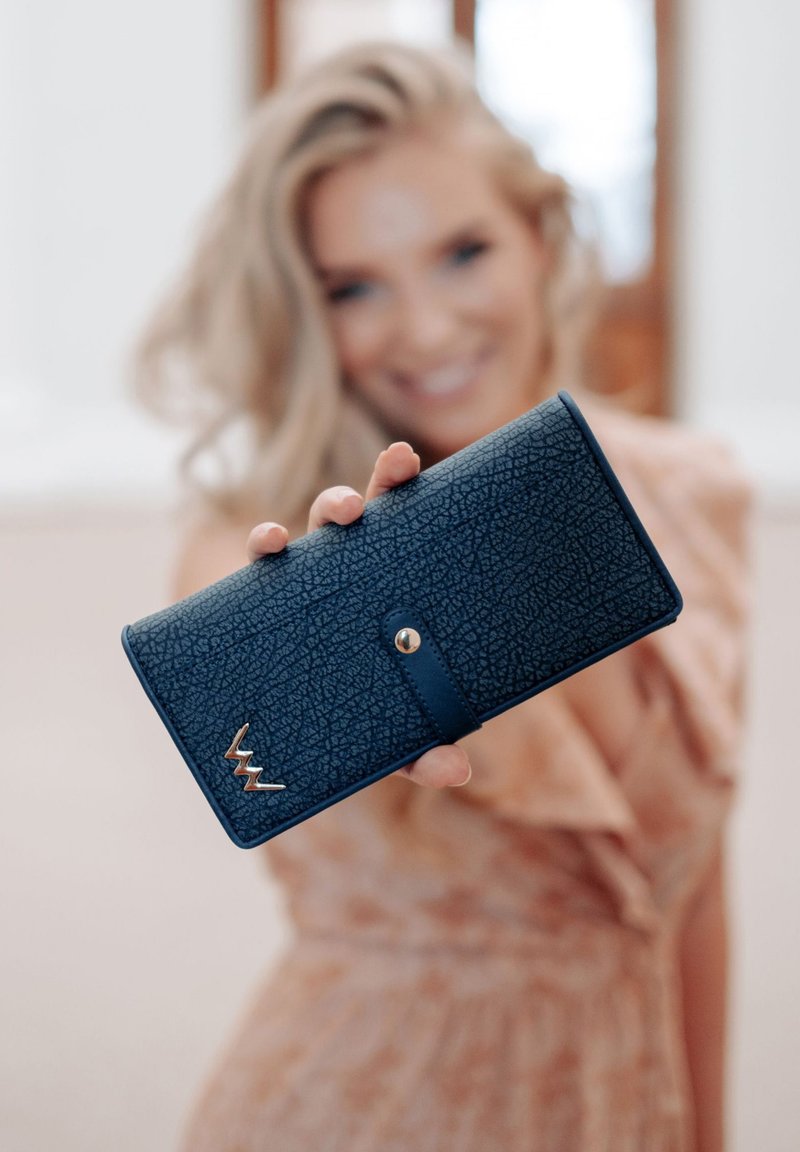 Dark blue wallet made of textured material with a gold accent logo and snap closure. Features a rectangular shape and smooth edges.