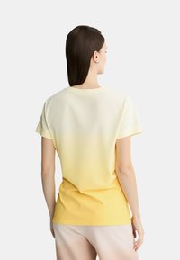 T-shirt giallo con gradiente, a maniche corte e scollatura rotonda. Tessuto morbido, che passa da un giallo chiaro a una tonalità più scura.
