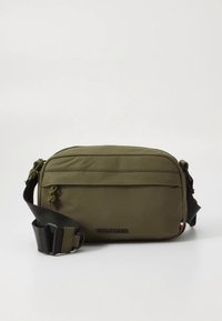 Olijfgroene crossbodytas van nylon, rechthoekige vorm, voorzien van een voorvak met ritssluiting, verstelbare riem en logodetail aan de voorkant.