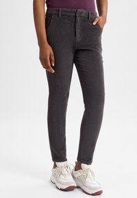 Grijze corduroy broek met slim fit, met voorzakken en een knoopsluiting. Gecombineerd met witte sneakers met beige accenten.