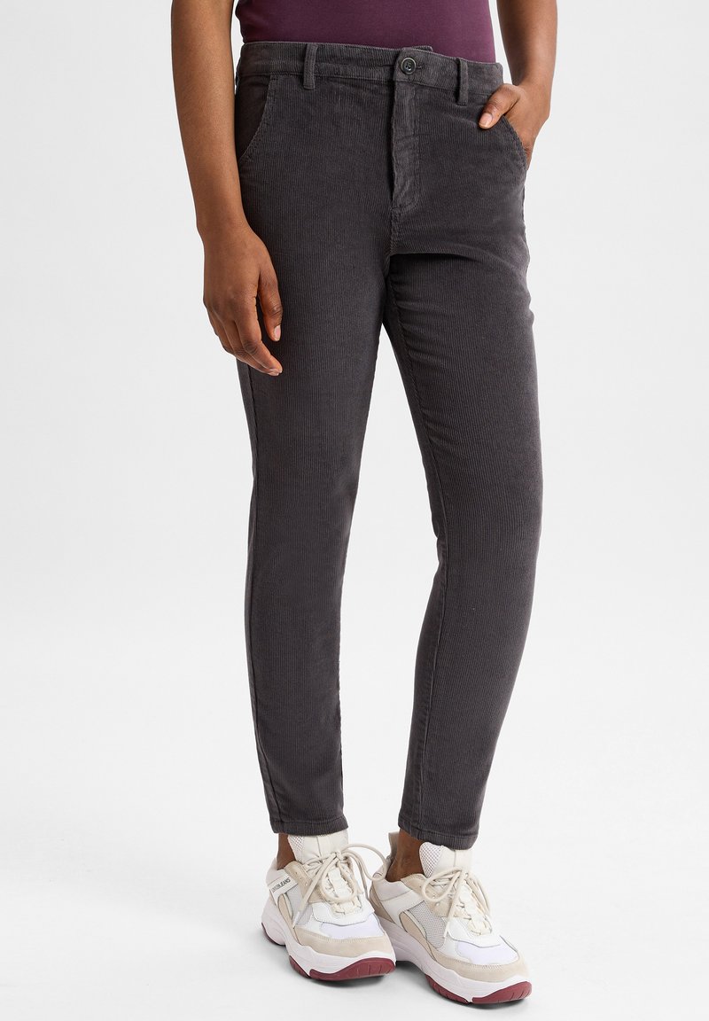 Grijze corduroy broek met slim fit, met voorzakken en een knoopsluiting. Gecombineerd met witte sneakers met beige accenten.