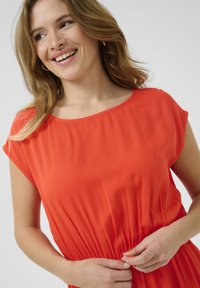 Red, short-sleeve dress made of lightweight fabric with a relaxed fit and gathered detail at the waist. Smooth texture against a neutral background.