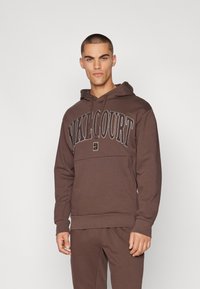 Sweatshirt castanho com capuz ajustável e bolso canguru. Apresenta o logótipo "NIKECOURT" em cor contraste. Tecido macio, corte relaxado.