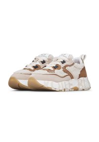 Beige and brown sneakers with fluffy texture, white laces, thick soles with patterned tread, and branded loops at the heel.
