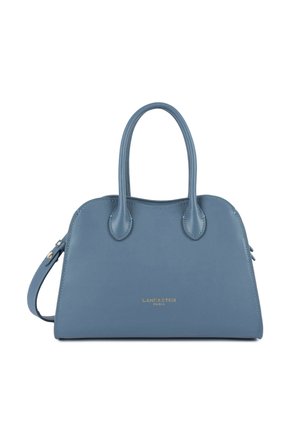 Sac à main Lancaster Paris en cuir bleu avec doubles poignées, forme incurvée élégante et bandoulière amovible sur fond blanc.
