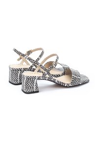Sandalias de tacón con un patrón en blanco y negro y un acabado texturizado, que presentan correas cruzadas y un diseño de tacón cuadrado.