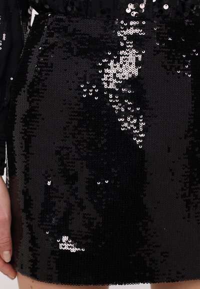 Čierna mini sukňa z flitrov s hladkou textúrou. Obsahuje malé lesklé okrúhle flitre usporiadané tesne vedľa seba, čo vytvára reflexívny povrch.