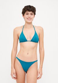 Teal bikini with a triangular top and minimal coverage, featuring thin straps and a smooth texture. Simple, solid color design.