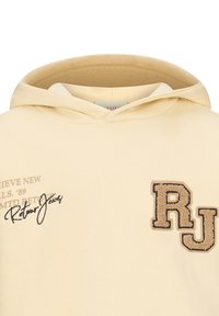 Kremowa bluza z kapturem z teksturowaną naszywką z logo "RJ", ozdobnym napisem w jasnobrązowym kolorze oraz regulowanym kapturem.