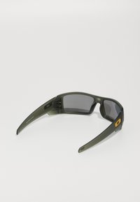Ochelari de soare cu o ramă verde olive mată, lentile gri închis și un mic logo portocaliu pe lateral. Au un design învelit pentru performanță.