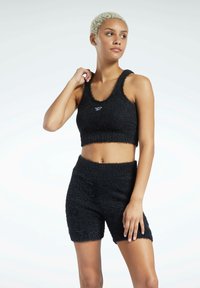 Svart strikket sport BH og matchende shorts-sett, laget av fuzzy stoff med en strukturert overflate. Har en logo på forsiden av BH-en.