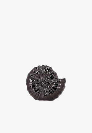 Glänzende schwarze Keramikschale in Form einer spiralförmigen Muschel mit strukturierten Rippen und welligem Rand vor weißem Hintergrund.