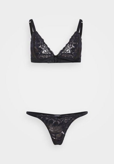 Schwarzer Spitzenslip mit dreieckigen Cups und verstellbaren Trägern, kombiniert mit einem passenden Spitzenstring, der ein florales Muster und minimale Bedeckung bietet.