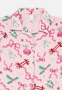 Ροζ πουκάμισο με κουμπιά και γιορτινές παραστάσεις, συμπεριλαμβανομένων φύλλων αγιόκληματος, κορδελών, μπάλων, καραμελών και γκι σε �πράσινο, κόκκινο και λευκό χρώμα.