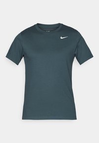 Lyhythihainen urheilupaita, joka on valmistettu teal-värisestä kankaasta, pyöreä kaula-aukko, vasemmassa rinnassa pieni valkoinen Nike-logo. Sujuva pinta.