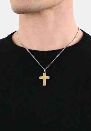 Collana in argento con pendente a croce in oro e argento, caratterizzata da un design elegante e una texture liscia, indossata sopra un maglione nero.