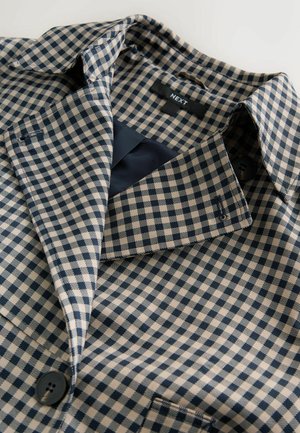 Marineblaue und cremefarbene karierten Stoff mit einem Kragen, ausgestattet mit einem einzelnen Knopf und einem glatten Innenfutter. Das Etikett trägt die Aufschrift "NEXT".