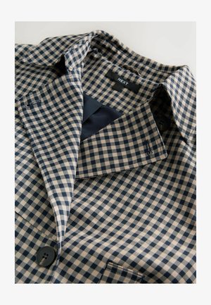 Tumši zils un krēmkrāsas rūtainas audums ar apkakli, vienu pogu un gludu iekšējo oderi. Etiķete ar uzrakstu "NEXT".