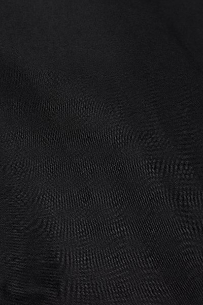 Gros plan d’un tissu noir texturé montrant un motif de tissage détaillé et des reflets subtils de lumière.