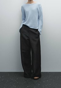 Light blue knit sweater with a boat neckline, paired with high-waisted black wide-leg trousers. Smooth texture, minimalist design, no patterns.