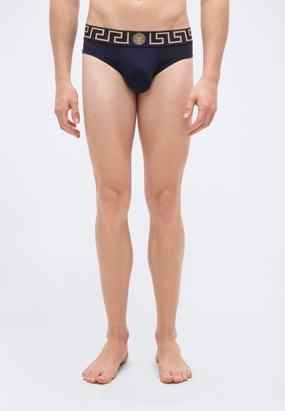 Culottes bleu marine avec un motif clé grec doré sur la ceinture et le logo central. Fabriquées en tissu doux, conçues pour une coupe ajustée.