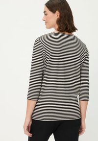 Gestreiftes Langarmoberteil mit schwarzen und cremefarbenen horizontalen Streifen, rundem Ausschnitt und Dreiviertelärmeln, gefertigt aus weichem, flexiblem Stoff.
