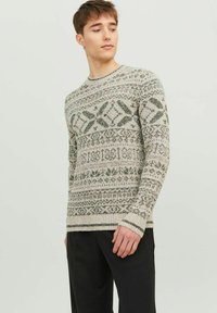 Strickpullover in hellem Beige mit grünen geometrischen Mustern. Rundhalsausschnitt, lange Ärmel, gerippte Bündchen und Saum. Strukturierter Baumwoll-Mischgarn.