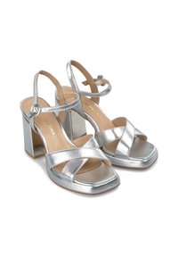 Stříbrné metalické sandály na vysokém podpatku s čtveratou špičkou, křížovými pásky, páskem kolem kotníku a masivním blokovým podpatkem se zrcadlovými akcenty.