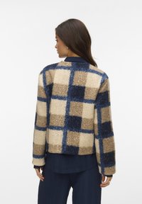 Wollige geruite jas in beige, bruin en blauwe tinten. Heeft een ronde halslijn en een losse pasvorm met lange mouwen, textuurstof.