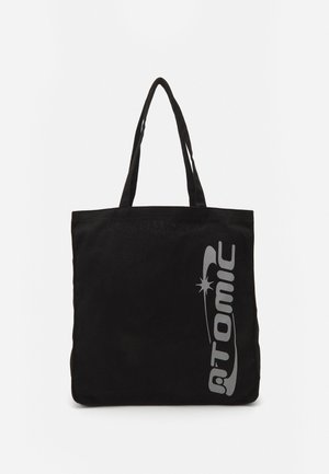 Black tote bag with gray "ATOMIC" logo. Made of durable fabric with two shoulder straps. Rectangular shape with a plain texture.