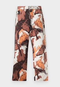 Nadrág, amelyen lófejek ismétlődő mintázata látható barna, fehér és narancssárga árnyalatokban, sima anyagból készült, egyenes szárú szabással.