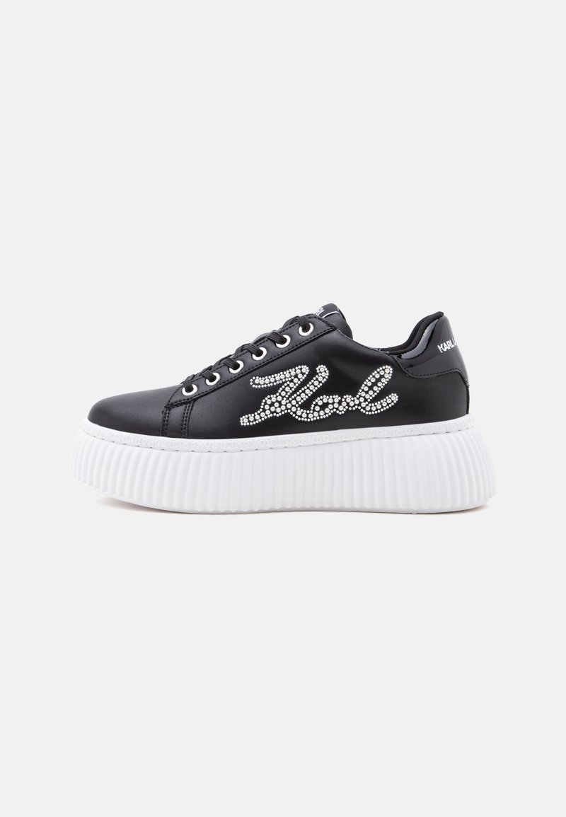 Μαύρο sneaker πλατφόρμα με λευκή χοντρή ραβδωτή σόλα και διακοσμητική επιγραφή με στρας στο πλάι, από την εξωτερική πλευρά.