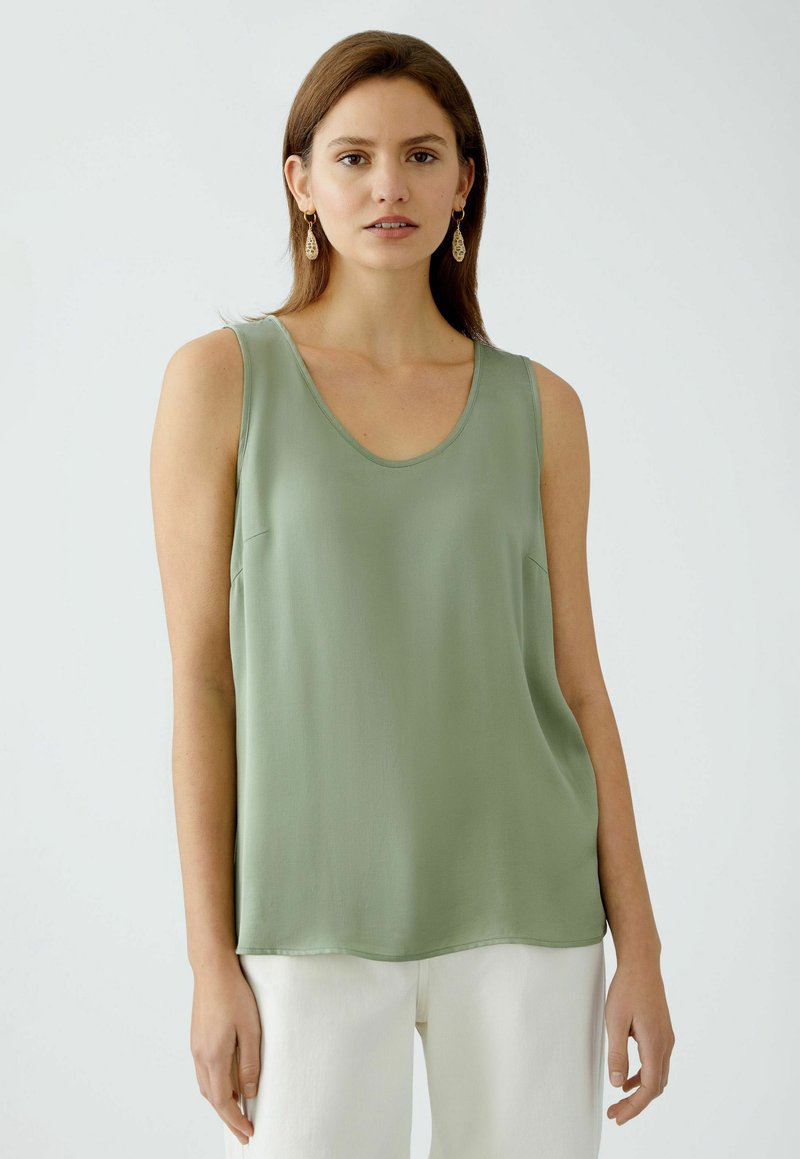 Haut sans manches vert clair avec un décolleté arrondi, fabriqué en tissu lisse ; présente une coupe décontractée et un subtil détail de couture latérale.