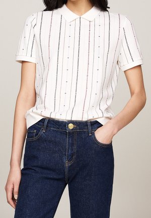 Hvid kortærmet skjorte med krave og vertikale striber i sort, grå og pink. Kombineret med mørkeblå jeans med en frontlomme.