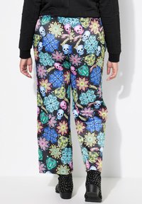 Pantaloni a vestibilità rilassata, colorati e con fantasia, caratterizzati da un design floreale e di teschi su uno sfondo nero. Il materiale sembra leggero e ha una texture liscia.