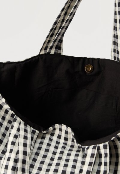 Τσάντα tote σε ασπρόμαυρο καρό σχέδιο gingham, με μαύρο εσωτερικό ύφασμα, μια μικρή εσωτερική τσέπη και χρυσό μαγνητικό κούμπωμα.