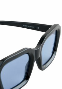 Ochelari de soare din plastic negru cu rame pătrate și lentile cu nuanță albastră. Caracteristici includ o suprafață texturată și detalii gravate de fabricație.