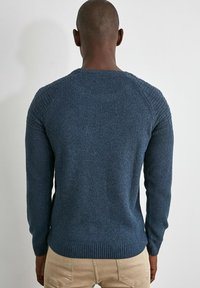 Mörkblå stickad tröja med texturerad baksida och ribbad nederkant, med raglansärmar och en mjuk, vävd tyglook.